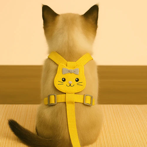Cat wearing a yellow harness with a smiling face design on a beige background